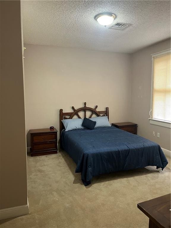 carpeted bedroom featuring visible vents, baseboards, and a textured ceiling