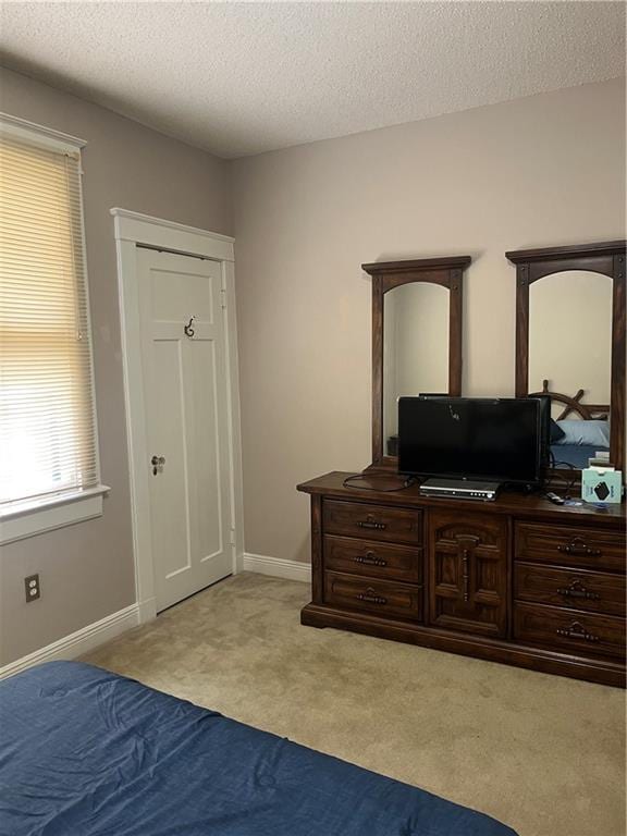 carpeted bedroom featuring baseboards and a textured ceiling