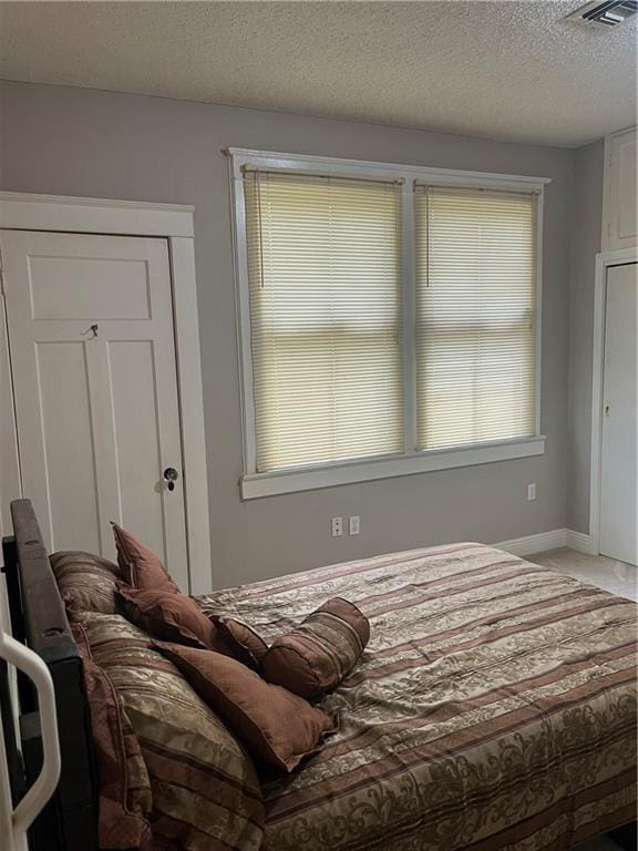 bedroom featuring visible vents, baseboards, and a textured ceiling