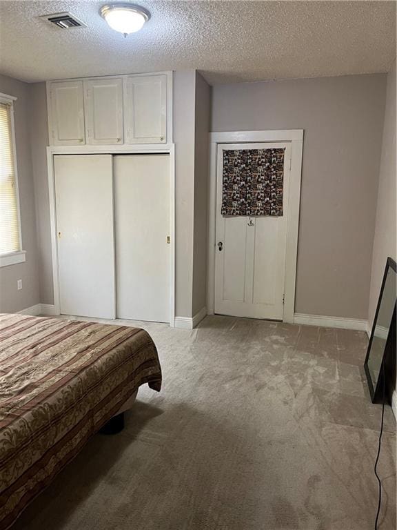 bedroom featuring visible vents, a textured ceiling, a closet, baseboards, and light colored carpet