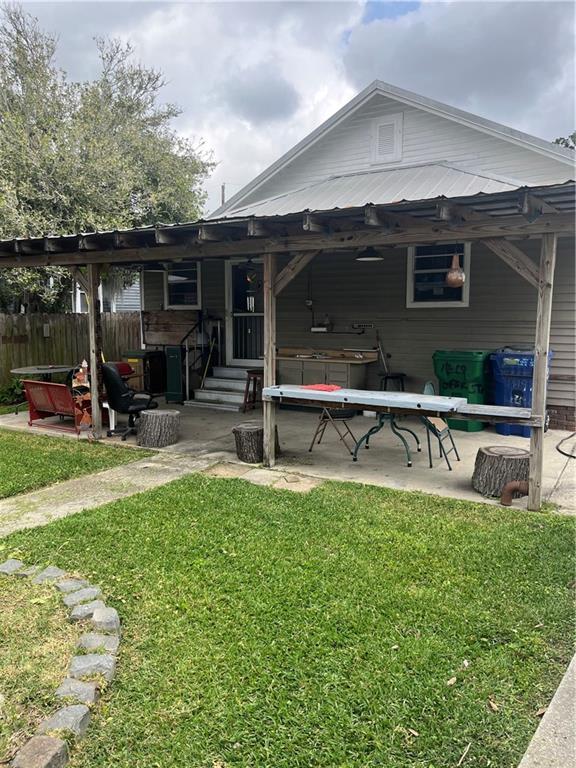 back of property featuring entry steps, a patio area, fence, and a lawn