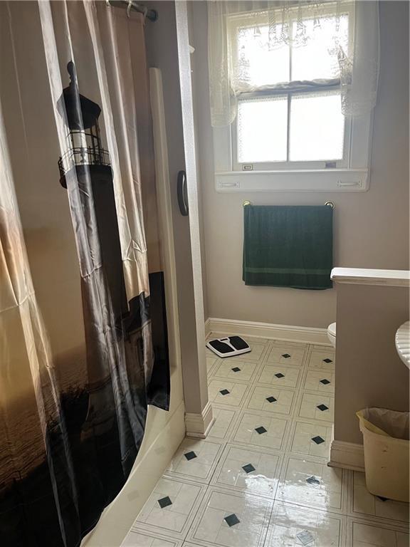 bathroom with baseboards, toilet, and a stall shower