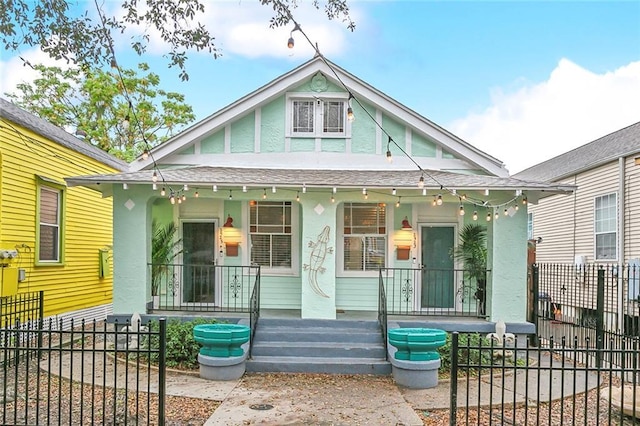 view of front of home with stucco siding, covered porch, and fence