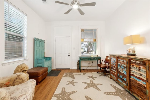 sitting room featuring plenty of natural light, wood finished floors, visible vents, and ceiling fan