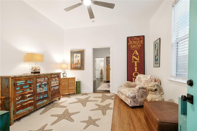 sitting room featuring vaulted ceiling, wood finished floors, baseboards, and ceiling fan