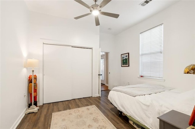 bedroom with wood finished floors, baseboards, visible vents, ceiling fan, and a closet