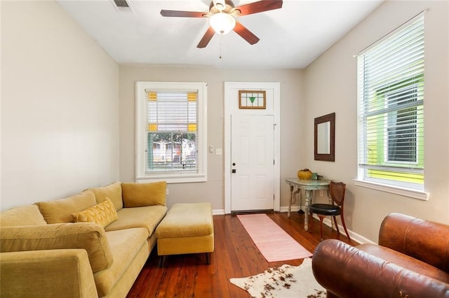 living room featuring dark wood-style floors, visible vents, baseboards, and ceiling fan