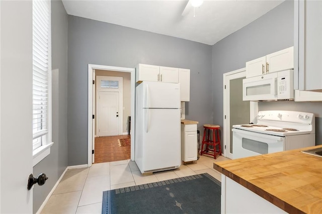 kitchen featuring light tile patterned flooring, white cabinets, white appliances, and butcher block counters