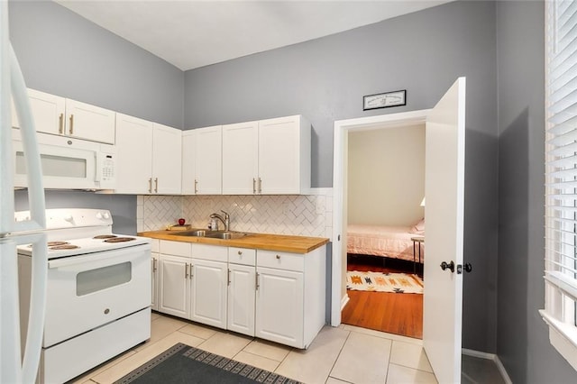 kitchen featuring decorative backsplash, light tile patterned flooring, white cabinets, white appliances, and a sink