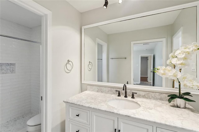 full bath featuring tiled shower, toilet, and vanity