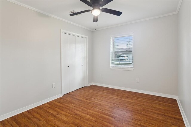 unfurnished bedroom featuring crown molding, wood finished floors, and baseboards