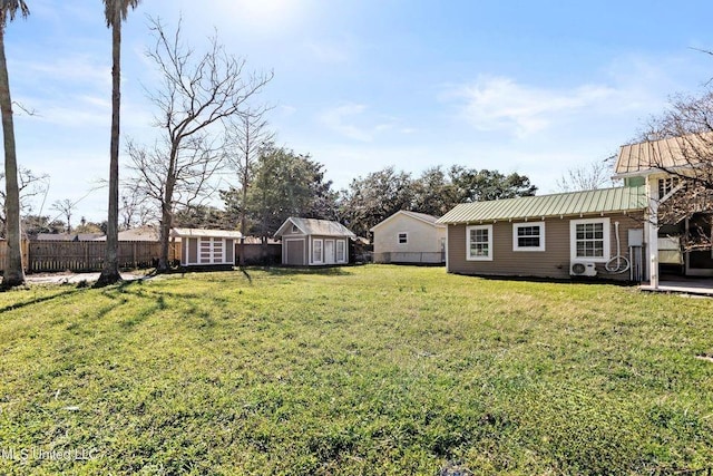 view of yard with a storage shed, fence, and an outbuilding