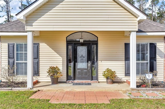 entrance to property featuring roof with shingles