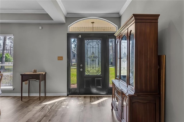 foyer entrance with baseboards, wood finished floors, and ornamental molding