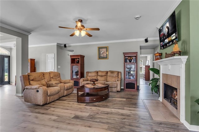 living room with a fireplace, crown molding, ceiling fan, and wood finished floors