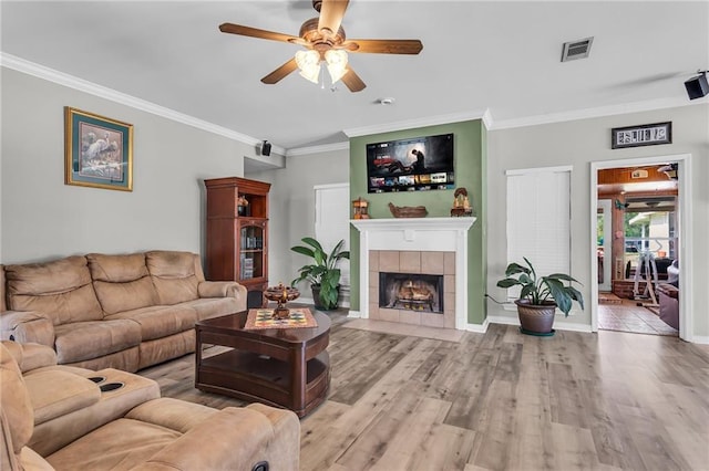31501 River Pines Dr, Springfield, LA 70462 - living room featuring ornamental molding, wood finished floors, baseboards, ceiling fan, and a tiled fireplace