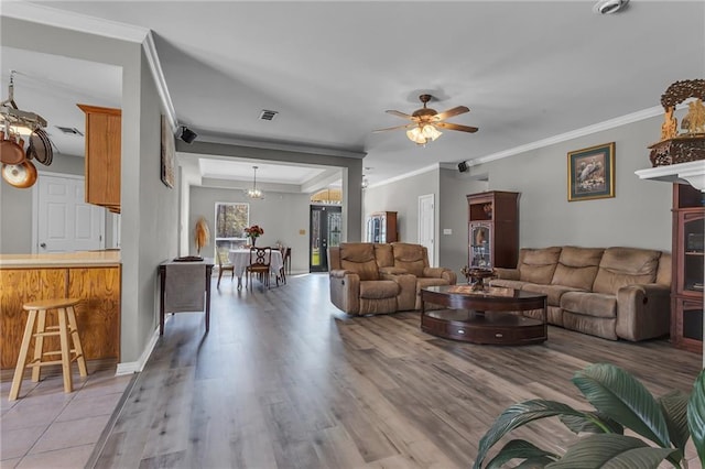 living area with light wood finished floors, visible vents, crown molding, baseboards, and ceiling fan