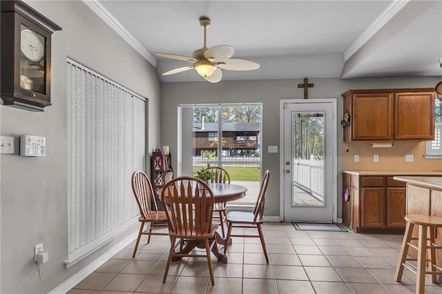 dining space featuring light tile patterned floors, baseboards, ornamental molding, and a ceiling fan