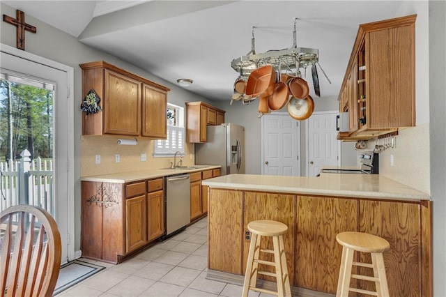 kitchen featuring a sink, stainless steel appliances, a peninsula, and light countertops