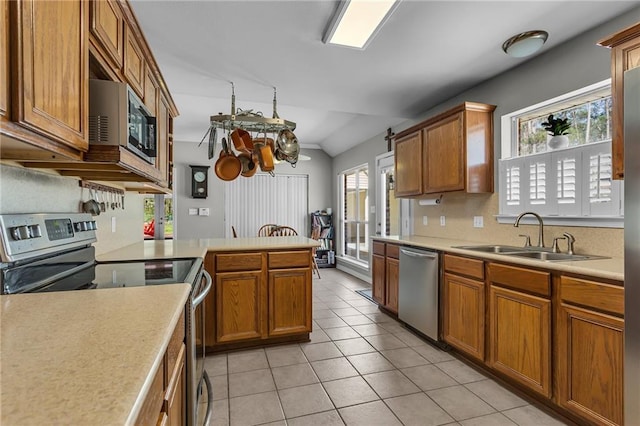 kitchen featuring brown cabinets, a sink, appliances with stainless steel finishes, light tile patterned flooring, and light countertops