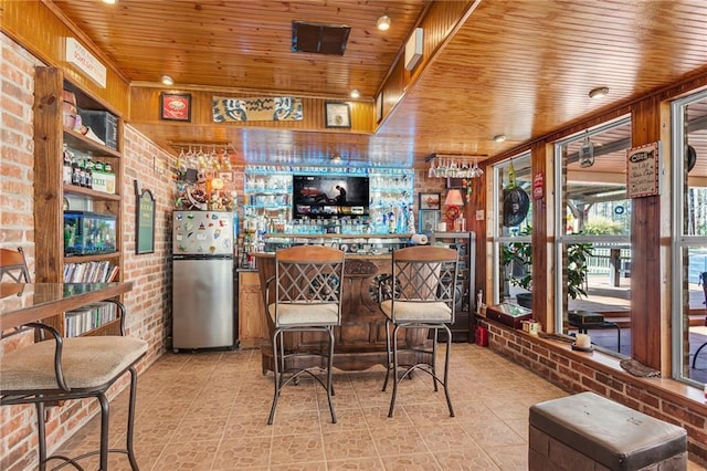 31501 River Pines Dr, Springfield, LA 70462 - kitchen featuring freestanding refrigerator, brick wall, wooden ceiling, and light tile patterned floors