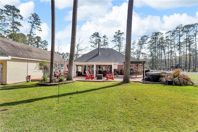 rear view of house with a patio, a lawn, fence, and a hot tub