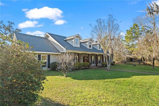 view of front of home featuring a shingled roof, a front yard, and fence