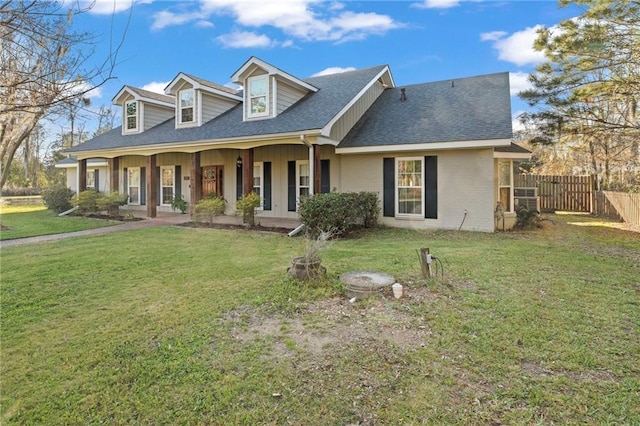 new england style home featuring a porch, a shingled roof, a front lawn, and fence