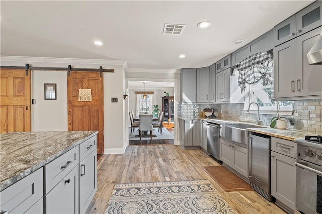 kitchen featuring visible vents, ornamental molding, gray cabinets, a sink, and stainless steel appliances