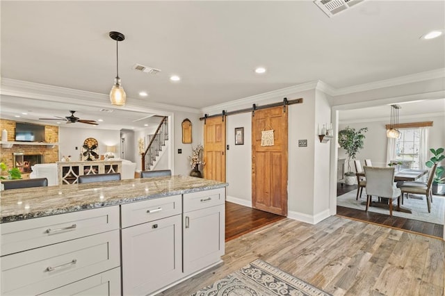 kitchen featuring light wood-style floors, a barn door, a fireplace, and visible vents