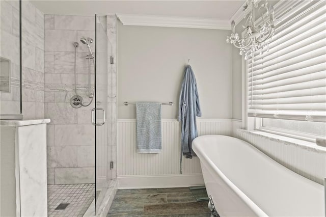 full bath featuring an inviting chandelier, a freestanding bath, ornamental molding, a shower stall, and wainscoting