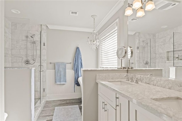 bathroom featuring a sink, a stall shower, a chandelier, and crown molding