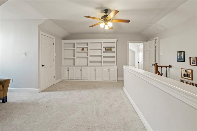 hallway with light colored carpet, baseboards, and lofted ceiling