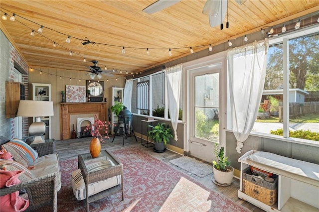 sunroom featuring rail lighting, a fireplace, ceiling fan, and wooden ceiling