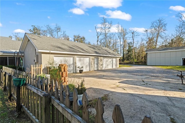 detached garage featuring driveway and fence