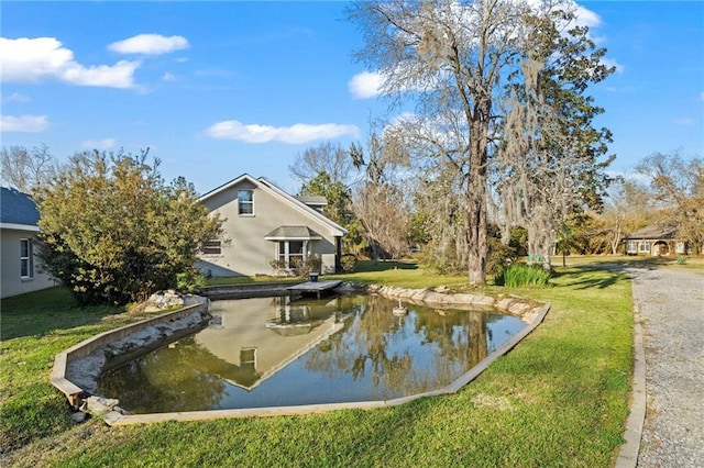 view of community with a yard and a small pond