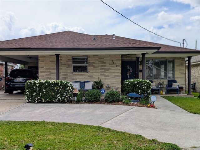 bungalow-style house featuring roof with shingles, a carport, and concrete driveway