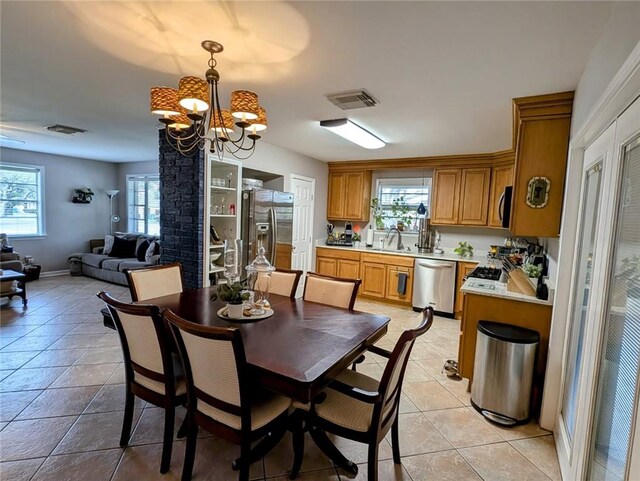 dining room with a chandelier, a wealth of natural light, light tile patterned flooring, and visible vents