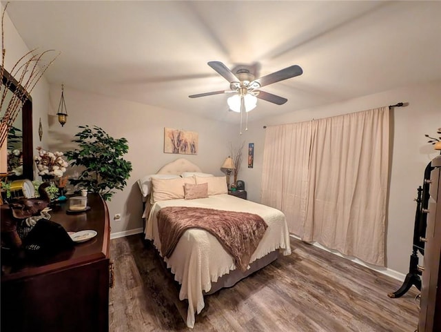 bedroom with ceiling fan, baseboards, and wood finished floors