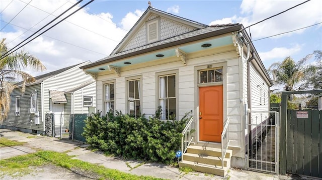 shotgun-style home with entry steps, a gate, and fence