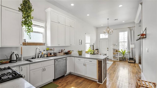 kitchen featuring a peninsula, stainless steel dishwasher, a notable chandelier, white cabinets, and a sink