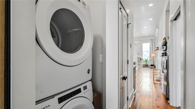 laundry room featuring recessed lighting, light wood-style floors, laundry area, and stacked washing maching and dryer