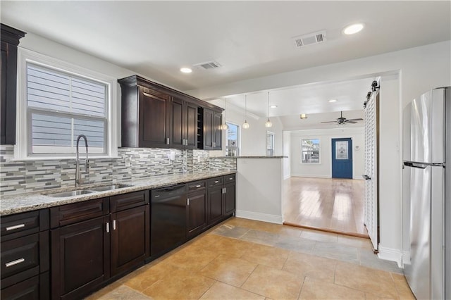 kitchen featuring visible vents, a sink, backsplash, freestanding refrigerator, and dishwasher