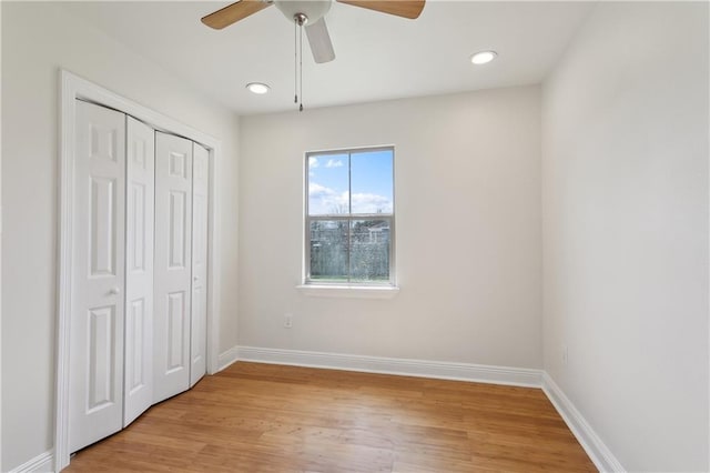 unfurnished bedroom with ceiling fan, a closet, baseboards, and light wood-style flooring