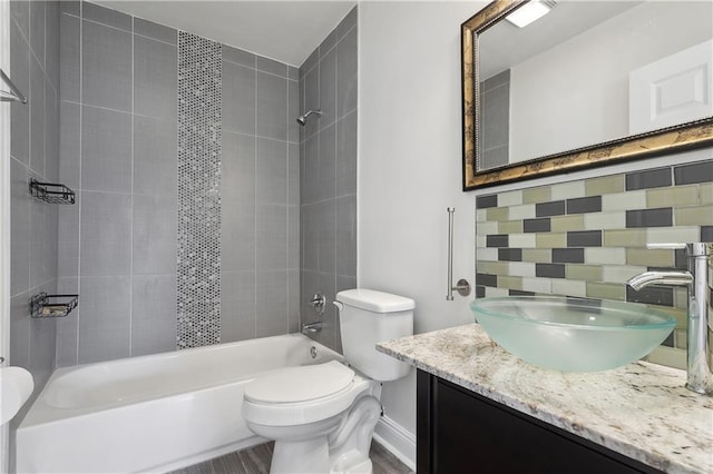 bathroom featuring decorative backsplash,  shower combination, toilet, and vanity