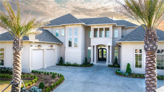 view of front of home with concrete driveway, french doors, a garage, and stucco siding