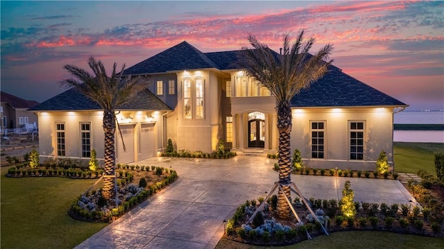 french country home featuring stucco siding, a yard, french doors, concrete driveway, and a garage