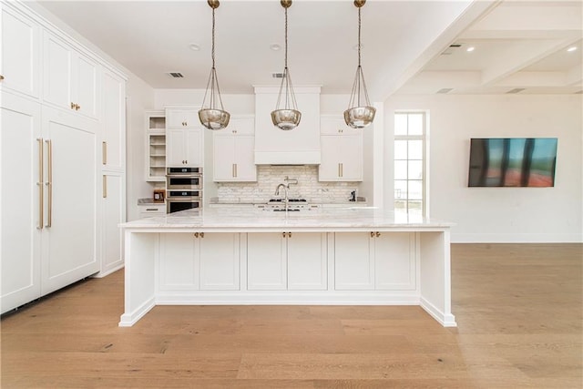 kitchen with white cabinets, tasteful backsplash, visible vents, and light wood-type flooring