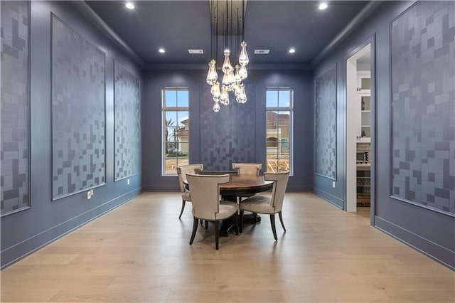 dining room featuring light wood-type flooring, visible vents, a chandelier, and crown molding