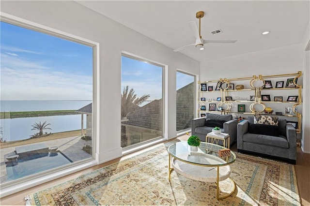 living area with visible vents, a water view, a ceiling fan, wood finished floors, and recessed lighting